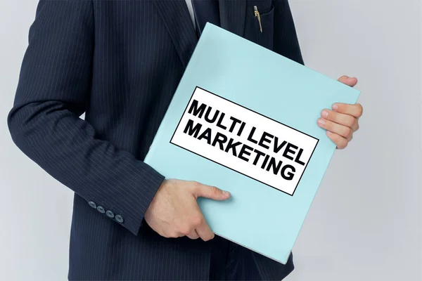 Business concept. A businessman holds a folder with documents, the text on the folder is - MULTI LEVEL MARKETING