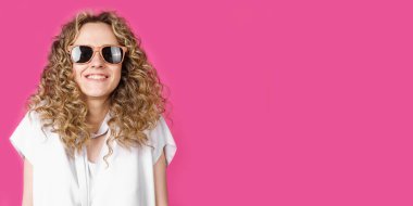 Gözlüklü, gülümseyen, omuz silken genç bir kadın. Kadın portresi. Pembe arka planda izole edilmiş