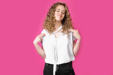 İnsanlar, gurur, kibir konsepti. Kendine güvenen, gururlu, yüksek başarılarından memnun, kendinden emin, başını dik tutan bir kadın, bir kahraman gibi. Pembe arka planda izole edilmiş