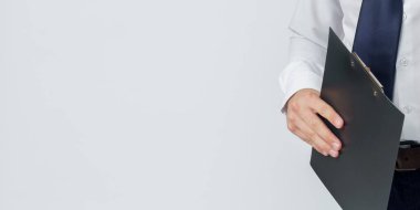 Bir iş adamı beyaz arka planda bir klasör tutuyor. Yüzü görünmüyor. İş ve finans kavramı