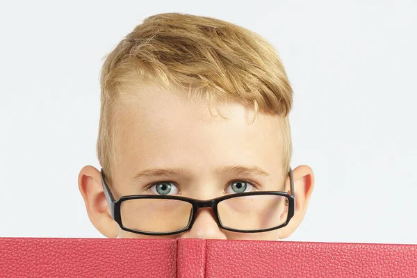 本の後ろに眼鏡をかけた少年が顔を隠している 孤立した背景 教育理念 — ストック写真