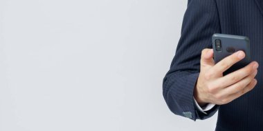 İş adamı beyaz bir arka planda elinde bir cep telefonu tutuyor. Yüzü görünmüyor. İş ve finans kavramı