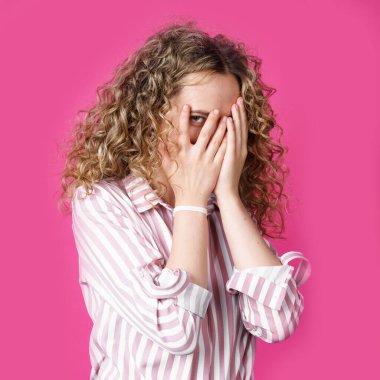 Utangaç, çekingen ya da utangaç güzel bir kızın portresi. Yüzü kaplayan ve parmaklarıyla röntgenleyen, kameraya bakan, meraklı. Vücut dili