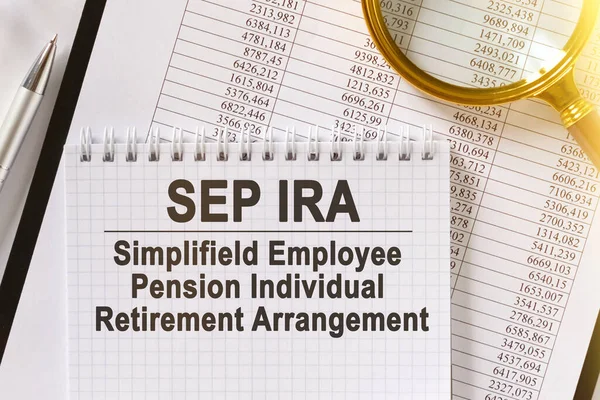 Masada mali raporlar, bir kalem, bir büyüteç ve yazılı bir defter var. SEP IRA. Simplifield İşçi Emekliliği. İş ve finans kavramı.