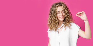 Küçük boy konsept. Aşırı neşeli genç bir kadın küçük bir şeyi şekillendirir, biraz daha ilgi ister, küçük görünmez bir nesneyi sergiler. İç modeller