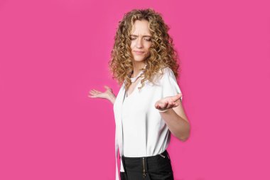 Genç kadın ellerini havaya kaldırdı. Pembe arka planda izole edilmiş