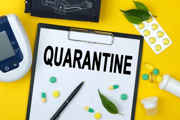Quarantin yazılı tablet. Yakınlarda bir tonometre, ilaçlar, vitaminler ve bir kalem var. Tıbbi konsept.