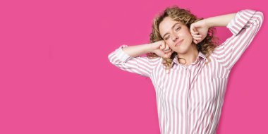 İşten sonra ellerini uzatan genç bir kadın. Pembe arka planda izole edilmiş