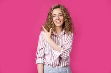 Genç ve güzel bir kadın parmağını sola doğru gösteriyor. İzole edilmiş pembe arkaplan