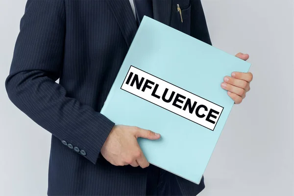Business concept. A businessman holds a folder with documents, the text on the folder is - INFLUENCE