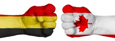 İnsanların mücadelesi kavramı. İki el birbirine kenetlenir ve birbirlerinin karşısındadır. Ülkelerin bayraklarının renklerine boyanmış eller. Kanada - Belçika