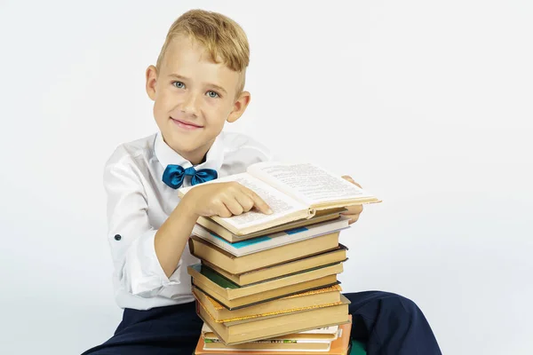 Een Schooljongen Zit Naast Een Stapel Boeken Glimlacht Terwijl Hij — Stockfoto