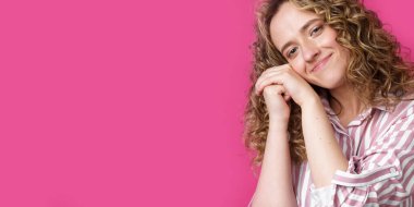 Mutlu ve mutlu kadın ellerini yüzünün yakınında tutuyor. Pembe arka planda izole edilmiş