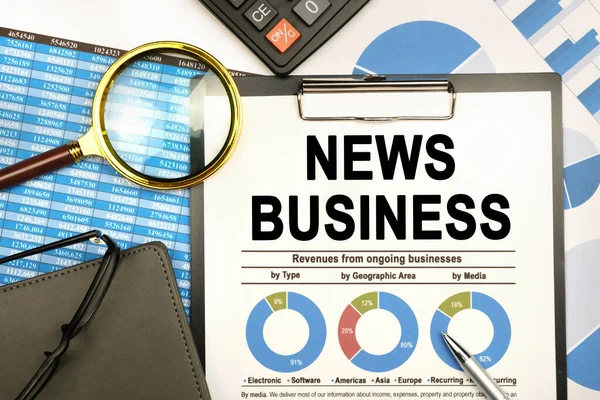 Finance and business concept. The businessman has on his desk graphs with reports, a notebook, a magnifying glass and a document with the inscription - NEWS BUSINESS