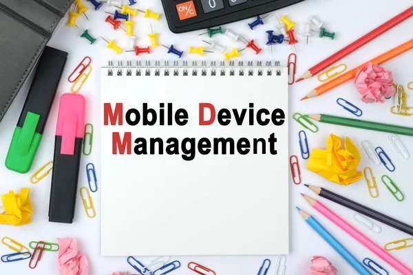 Business concept. On the table is a calculator, diary, markers, pencils and a notebook with the inscription - Mobile Device Management