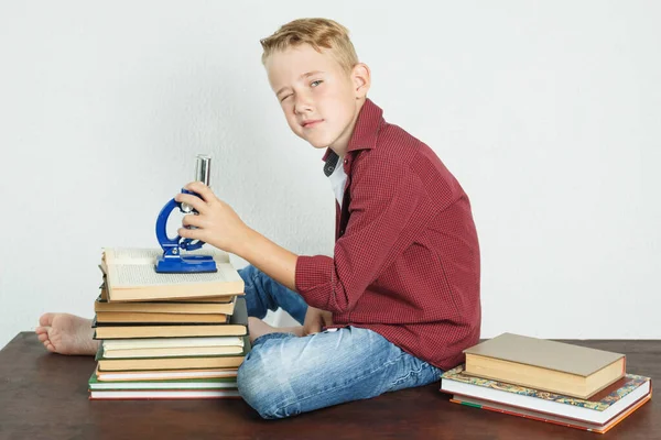 Écolier Assied Une Table Près Livres Tient Microscope Dans Ses — Photo