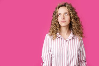 Genç ve güzel bir kadın boş fotokopi odasına bakarak düşünüyor. İzole edilmiş pembe arkaplan