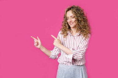 Neşeli bir kadın fotokopi odasını işaret eder, harika bir ilandan bahseder, yol verir ya da yön verir, çizgili bir gömlek giyer, hoş bir gülümsemesi vardır ve iyimser hisseder. Pembe arka planda izole edilmiş