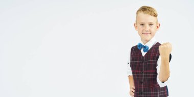 Bir okul çocuğunun portresi. Ellerini yumruğa sıkıp olumlu bir jest yapıyor. İzole edilmiş arka plan. Eğitim kavramı.