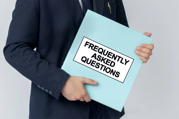 Business concept. A businessman holds a folder with documents, the text on the folder is - FREQUENTLY ASKED QUESTIONS