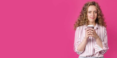 Elinde kahve tutan genç ve güzel bir kadın. İzole edilmiş pembe arkaplan