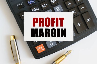 İş ve finans kavramı. Masanın üzerinde bir kalem, bir hesap makinesi ve metnin yazıldığı bir kartvizit var - PROFIT MARGIN