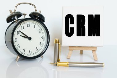 İş ve finans kavramı. Masanın üzerinde bir saat, bir kalem ve üzerinde CRM yazan bir kart var. CUSTOMER İLİŞKİLİK MERKEZİ