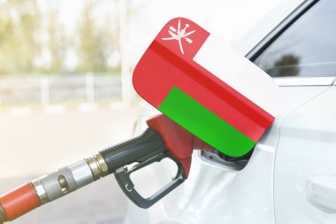 Enerji ve ekonomi kavramı. Arabanın benzin deposunda Umman bayrağı var. Depoda da benzin pompası var..