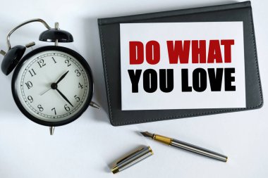 İş ve olumlu kavram. Masanın üzerinde bir saat, bir kalem, bir defter ve üzerine yazı yazılmış bir kart var.