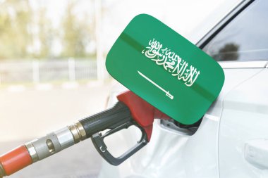 Enerji ve ekonomi kavramı. Arabanın benzin deposunda Suudi Arabistan bayrağı var. Depoda da benzin pompası var..