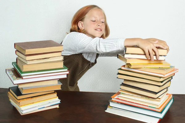 Education concept. A teenage girl takes books from a stack of books on the table.