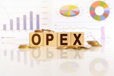 OPEX kelime ahşap küpler üzerinde, küpler yansıtıcı bir yüzey üzerinde duruyor, arka planda bir iş diyagramı var. İş ve finans kavramı