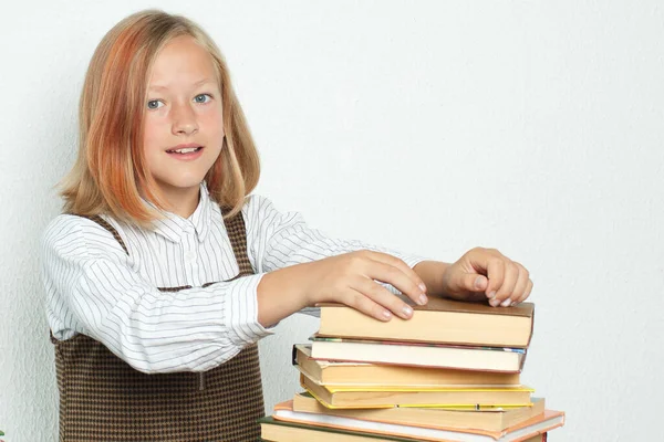 教育の概念 10代の女の子はテーブルの上の本の山から本を取ります — ストック写真
