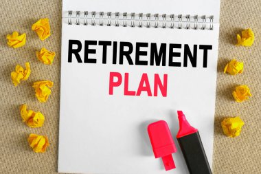 İş konsepti. Metin defterde yazılı - Emeklilik Planı. Defterin üzerinde bir işaret var, yanında buruşuk sarı kağıt var..