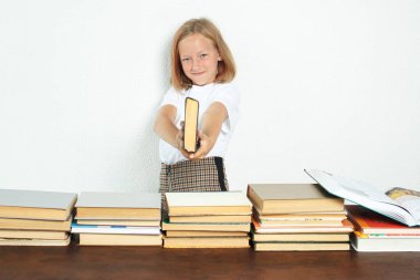 Eğitim konsepti. Öğrenci elinde bir tabanca gibi bir kitap tutuyor. Kitaplar yakınlarda.