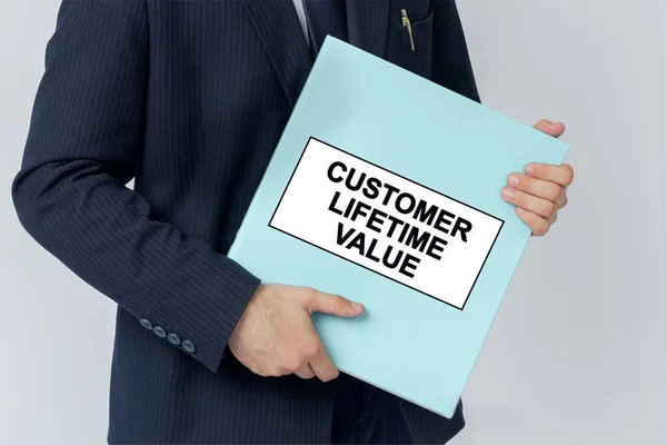 Business concept. A businessman holds a folder with documents, the text on the folder is - CUSTOMER LIFETIME VALUE