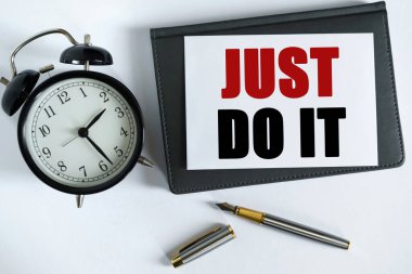 İş ve olumlu kavram. Masanın üzerinde bir saat, bir kalem, bir defter ve üzerine metin yazılan bir kart var.