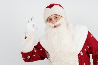 Noel ve Yeni Yıl konsepti. Noel Baba parmaklarıyla iyi bir jest yapıyor. İzole edilmiş arkaplan.