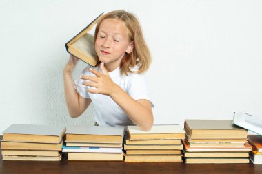 Eğitim konsepti. Öğrenci masada oturuyor, kafasından bir kitap düşüyor. Kitaplar yakınlarda.