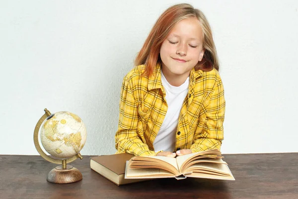 Education concept. A student reads a book. Near books and a globe