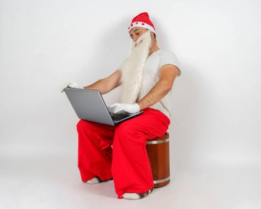 Noel ve Yeni Yıl konsepti. Noel Baba masasında oturuyor ve bilgisayar başında çalışıyor..