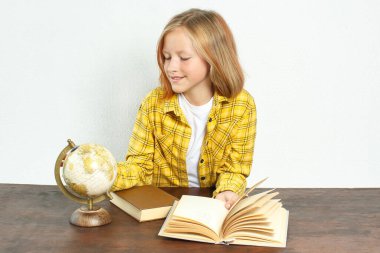 Eğitim konsepti. Öğrenci masaya oturur ve küreye bakar. Kitapların ve kürenin yanında.