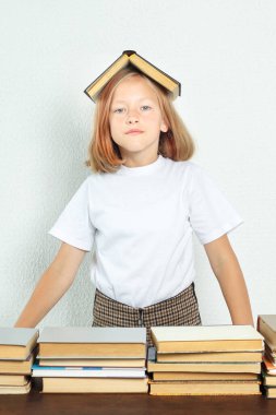 Eğitim konsepti. Öğrenci kitabı onun kafasına koydu. Masanın yanında kitaplar var.