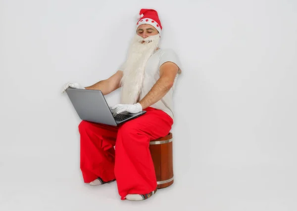 クリスマスと新年のコンセプト サンタクロースは彼の机に座ってコンピュータで仕事をしています — ストック写真