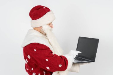 Noel ve Yeni Yıl konsepti. Noel Baba masasında oturuyor ve bilgisayar başında çalışıyor..