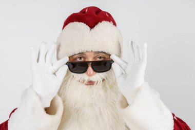 Tatiller ve Noel konsepti. Noel Baba gözlüğünü eliyle ayarlar. Beyazda izole edilmiş