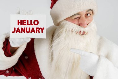 Yeni yıl ve Noel konsepti. Noel Baba elinde metin olan bir kart tutuyor - Merhaba JANUARY