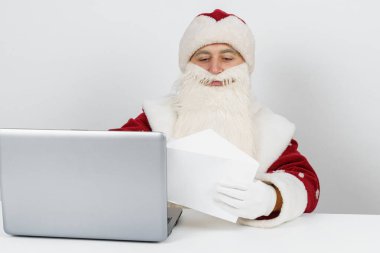 Noel ve Yeni Yıl konsepti. Noel Baba masasında oturuyor ve mektupları okuyor..