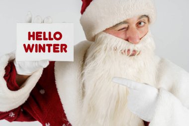 Yeni yıl ve Noel konsepti. Noel Baba elinde metin olan bir kart tutuyor - Merhaba Kışcı