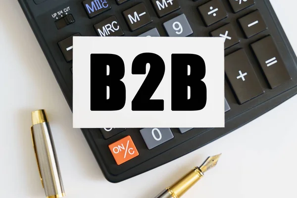 Business and finance concept. On the table there is a pen, a calculator and a business card on which the text is written B2B. BUSINESS TO BUSINESS
